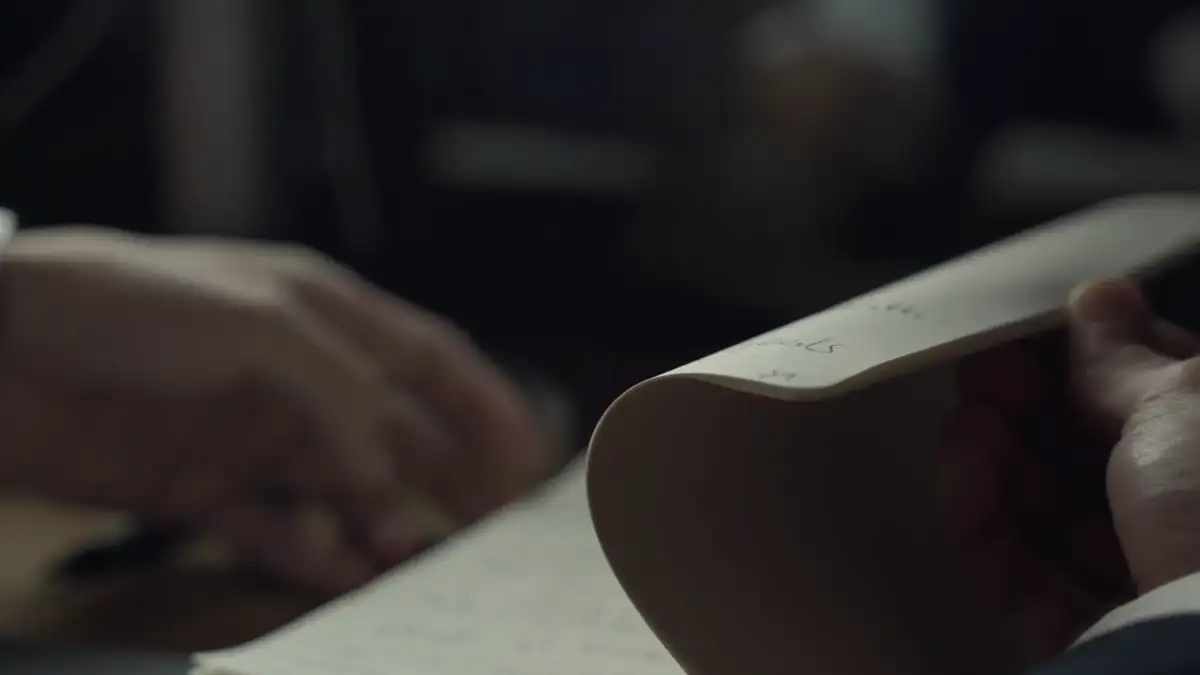 Hands turning the pages of a notebook in low light