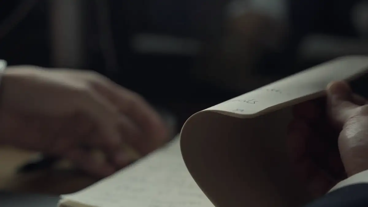 Hands turning the pages of a notebook in low light