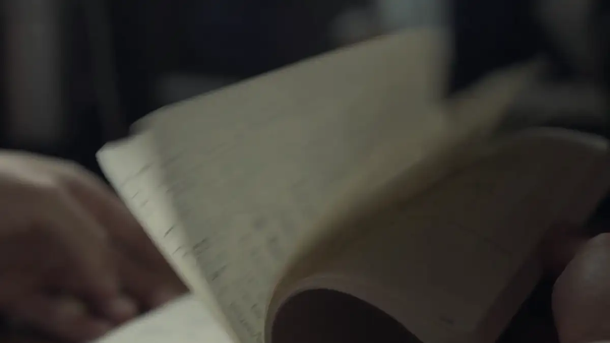 Hands turning the pages of a notebook in low light